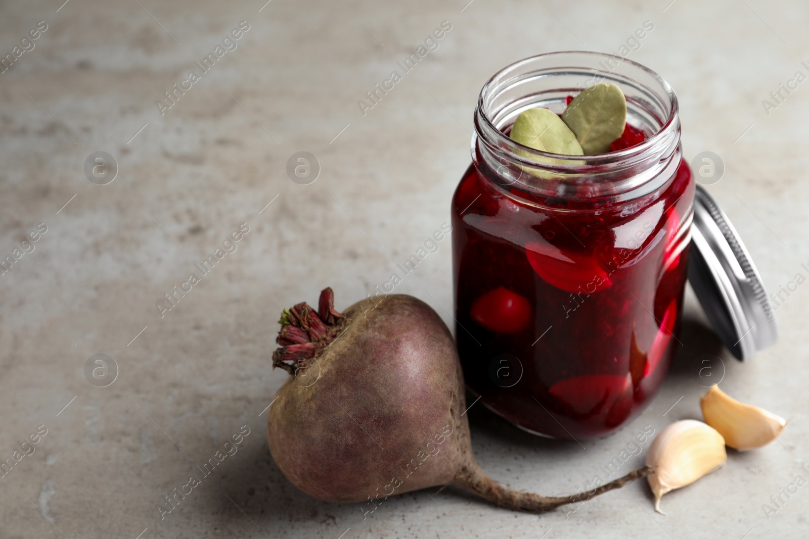 Photo of Pickled beets in glass jar on light table, space for text