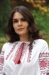 Photo of Beautiful woman in embroidered shirt outdoors. Ukrainian national clothes