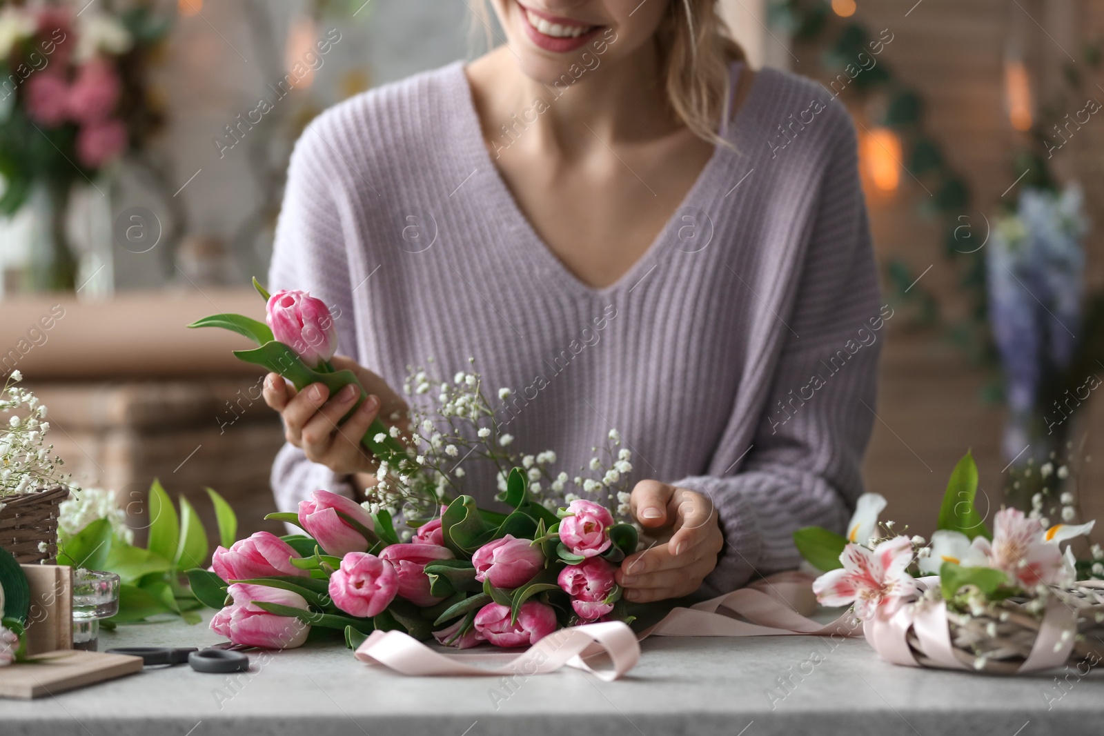 Photo of Female decorator creating beautiful bouquet at table