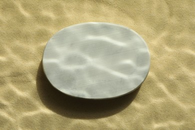 Photo of Stylish presentation for product. Stone podium on sand, top view