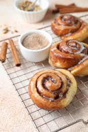 Photo of Tasty cinnamon rolls and sticks on beige textured table