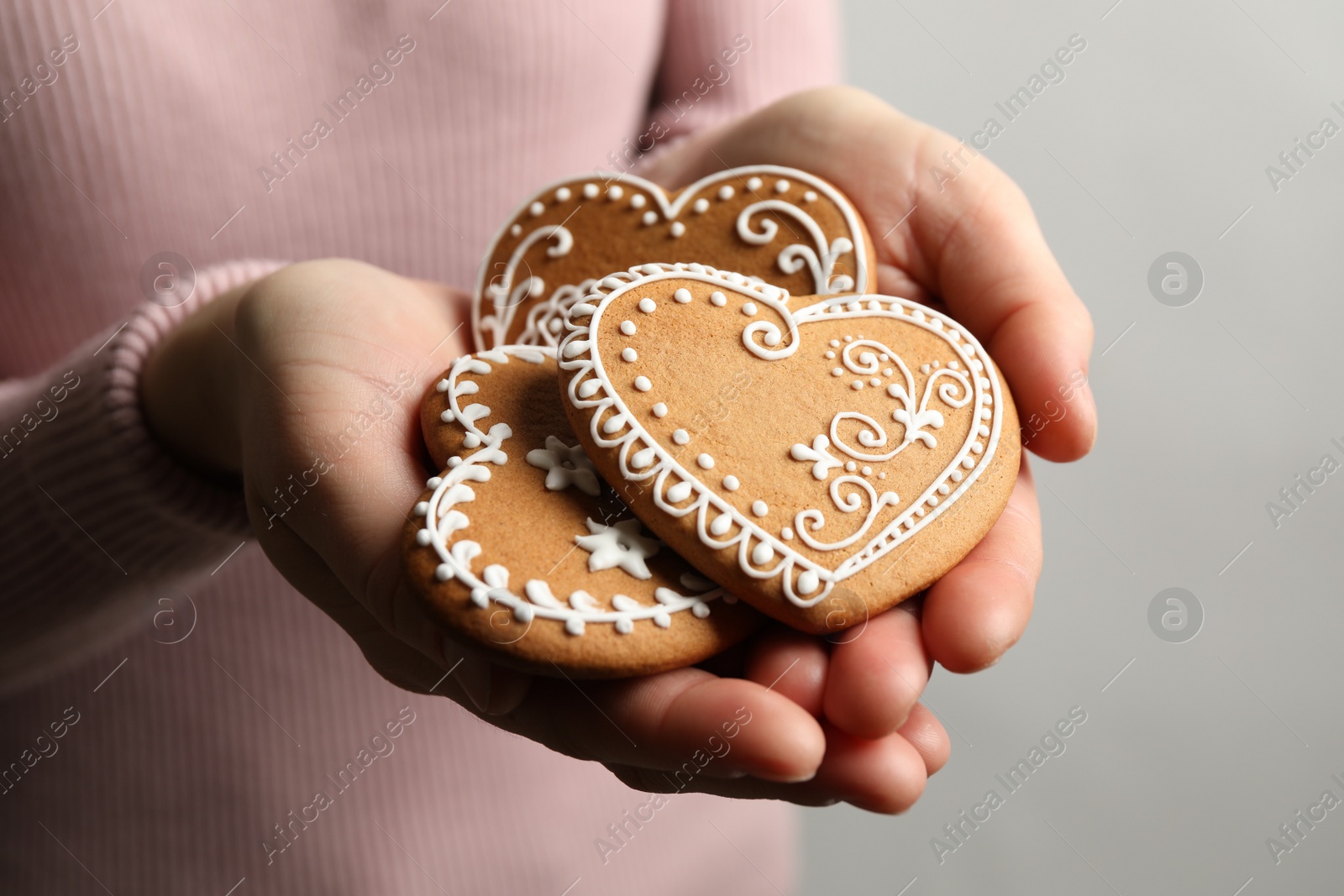 Photo of Woman holding tasty heart shaped gingerbread cookies, closeup