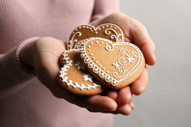 Woman holding tasty heart shaped gingerbread cookies, closeup