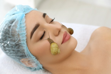 Photo of Young woman receiving snail facial massage in spa salon, closeup