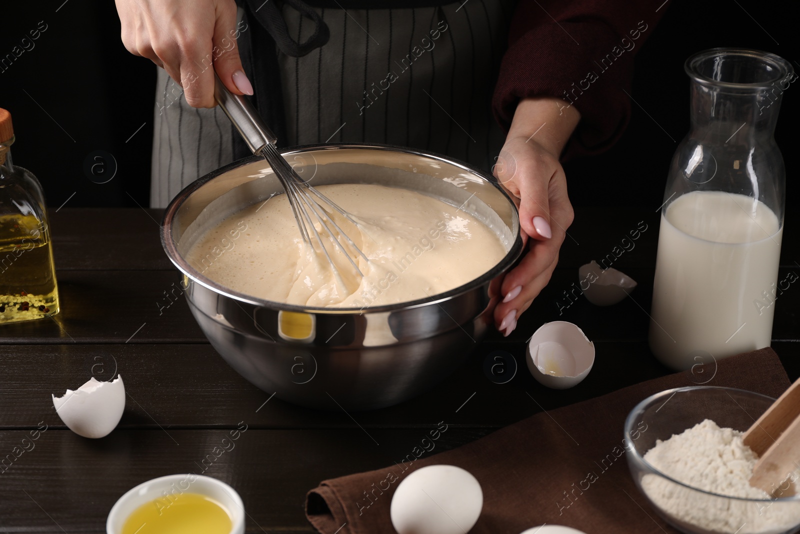 Photo of Woman making dough with whisk in bowl at table, closeup