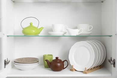 Open kitchen cabinet with different clean dishware