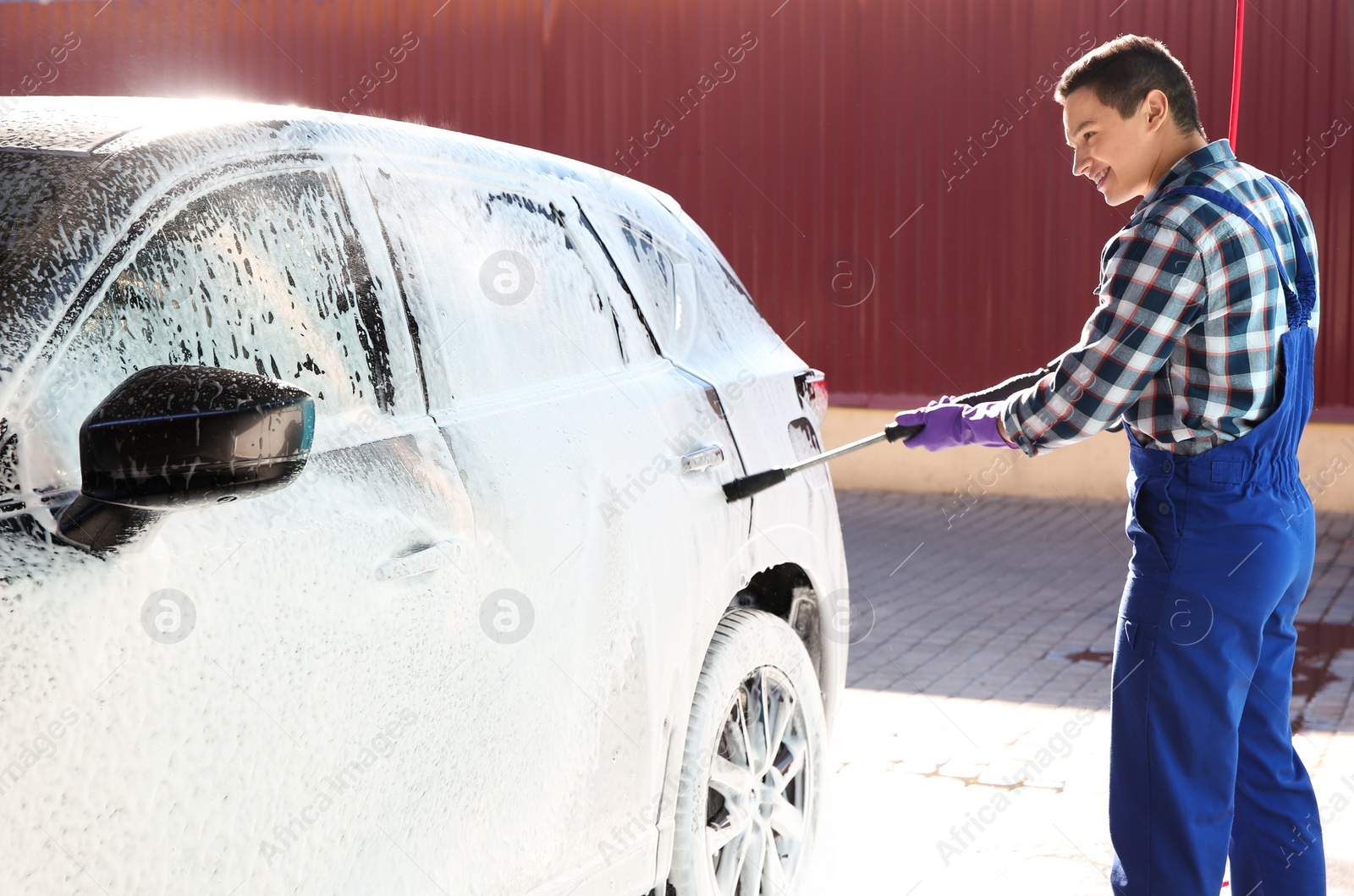 Photo of Worker cleaning automobile with high pressure water jet at car wash