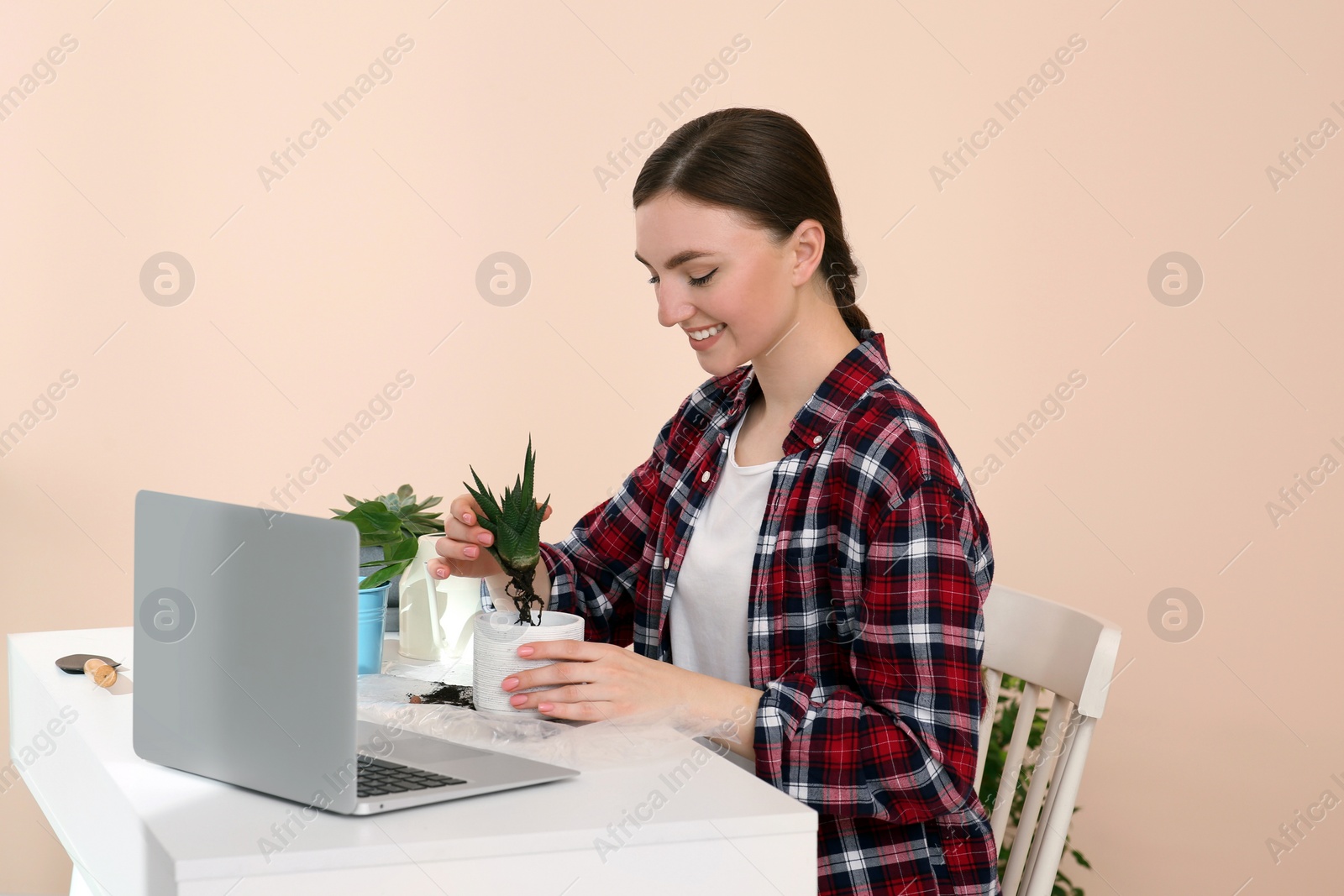 Photo of Woman taking care of plant following online gardening course at home. Time for hobby