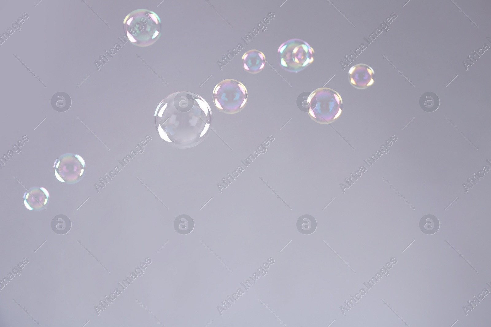 Photo of Beautiful translucent soap bubbles on grey background. Space for text