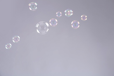 Beautiful translucent soap bubbles on grey background. Space for text