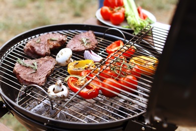 Photo of Modern grill with meat and vegetables outdoors, closeup