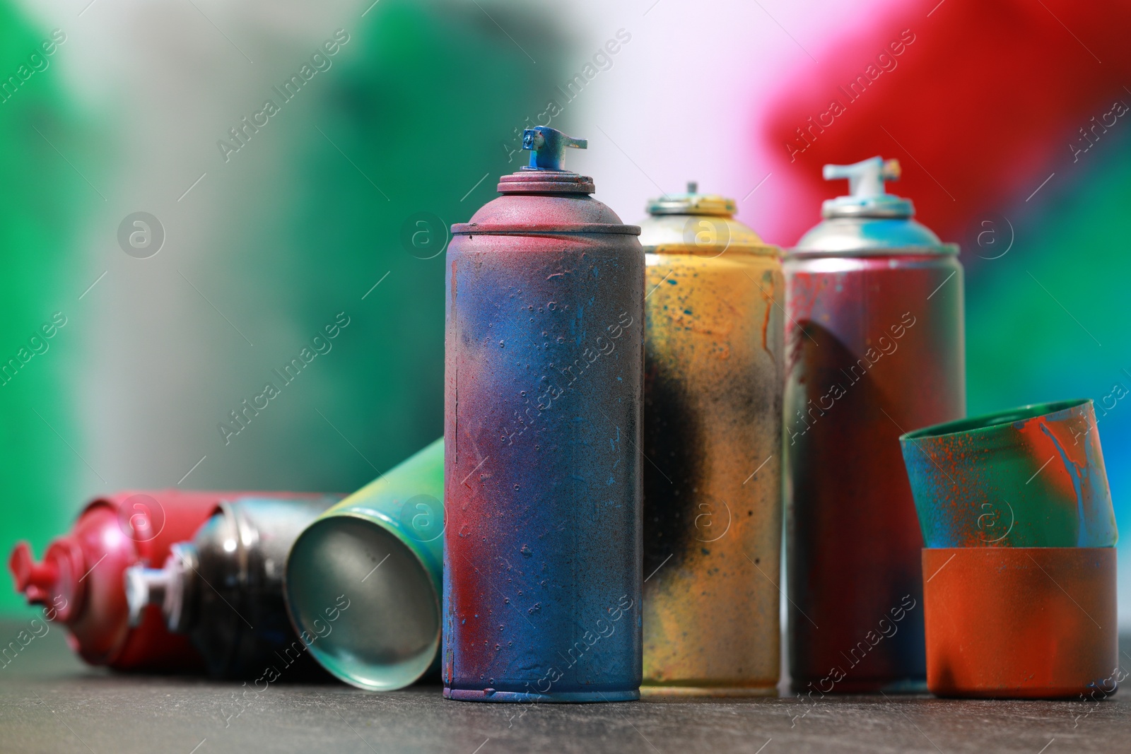 Photo of Many spray paint cans on gray surface against color background