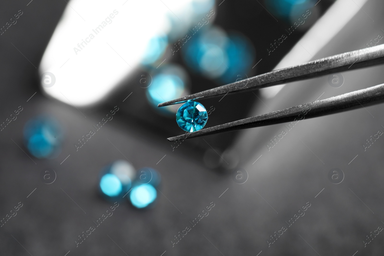 Photo of Tweezers with beautiful gemstone on blurred background