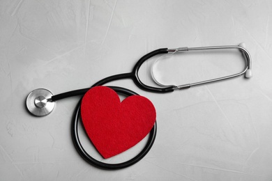 Photo of Stethoscope and red heart on gray background, top view. Cardiology concept