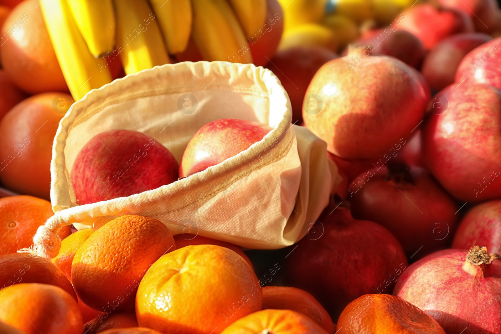 Photo of Cotton eco bag with pomegranates on fruits. Life without plastic