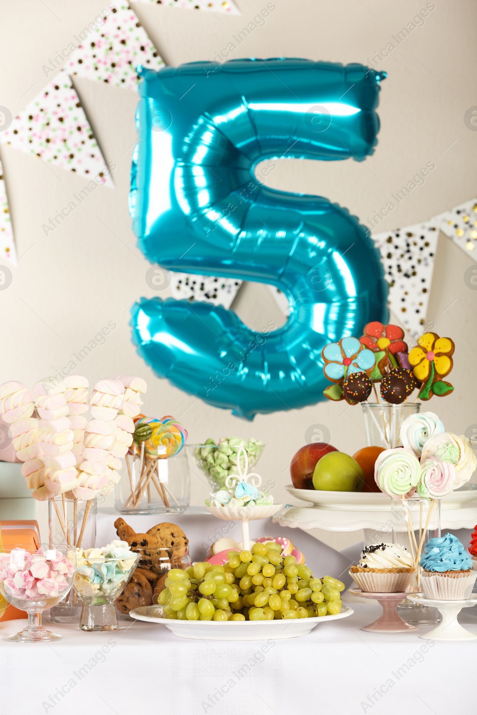 Photo of Blue number five balloon over table with delicious treats at Birthday party indoors