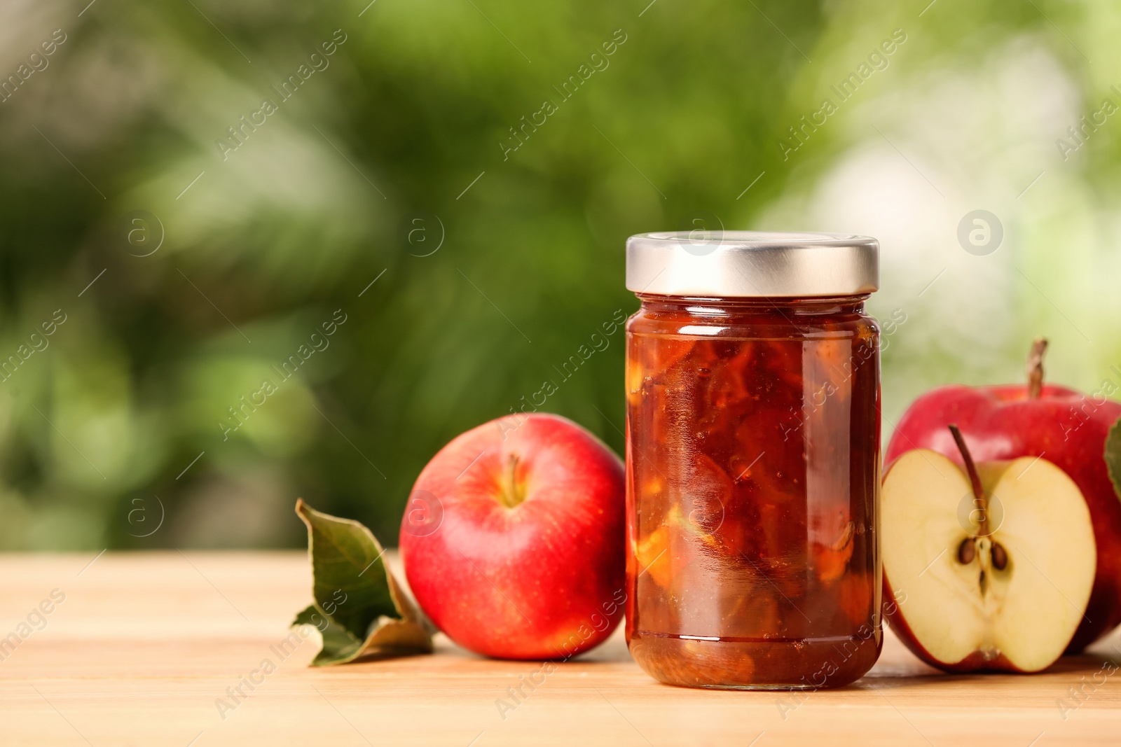 Photo of Delicious apple jam and fresh fruits on wooden table. Space for text