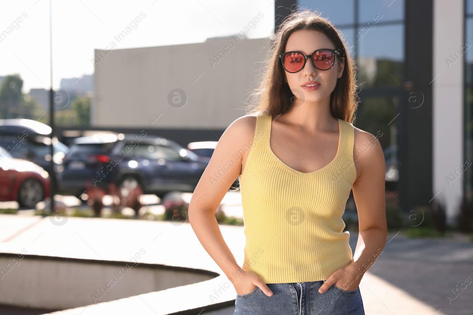 Photo of Beautiful woman in sunglasses on city street, space for text