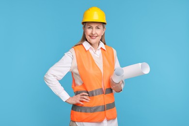 Photo of Architect in hard hat with drafts on light blue background