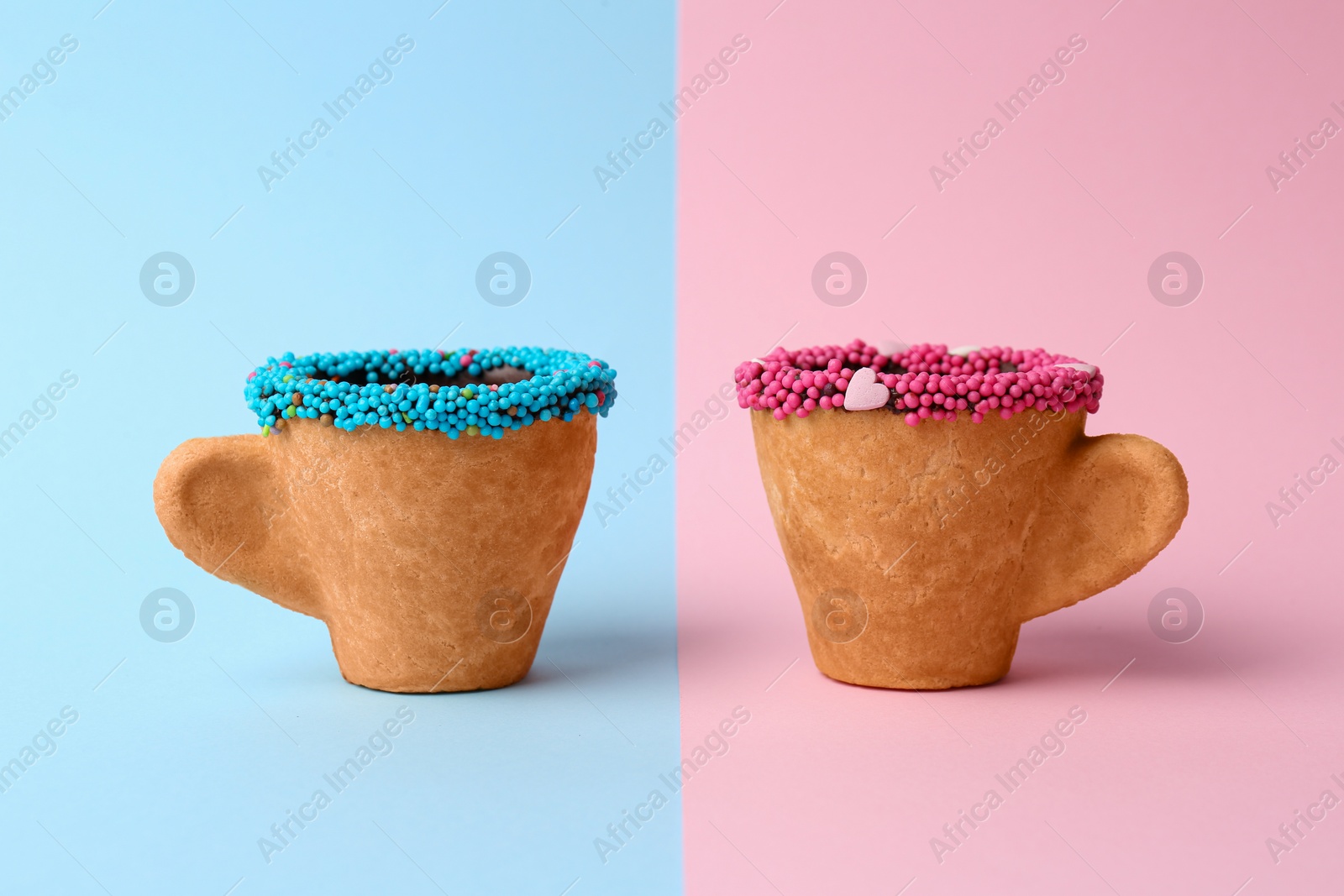 Photo of Delicious edible biscuit coffee cups decorated with sprinkles on color background