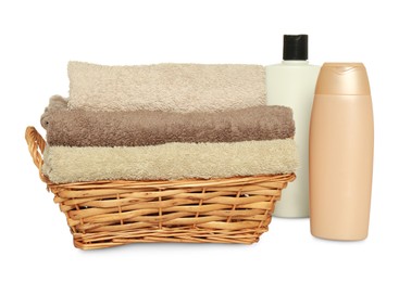 Photo of Wicker basket with folded soft terry towels and cosmetic products on white background