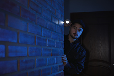 Photo of Male security guard with flashlight in dark corridor