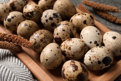 Photo of Wooden tray with quail eggs on table, closeup