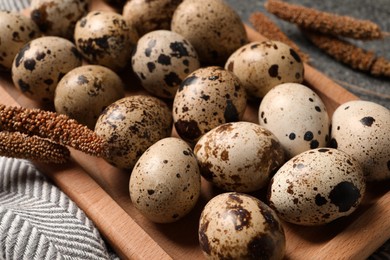 Wooden tray with quail eggs on table, closeup