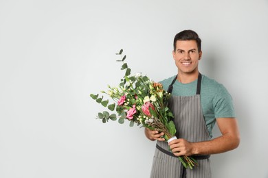 Photo of Florist with beautiful bouquet on light background, space for text