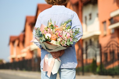 Photo of Man hiding beautiful flower bouquet behind his back on street