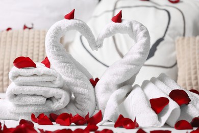 Photo of Honeymoon. Swans made with towels and beautiful rose petals on bed