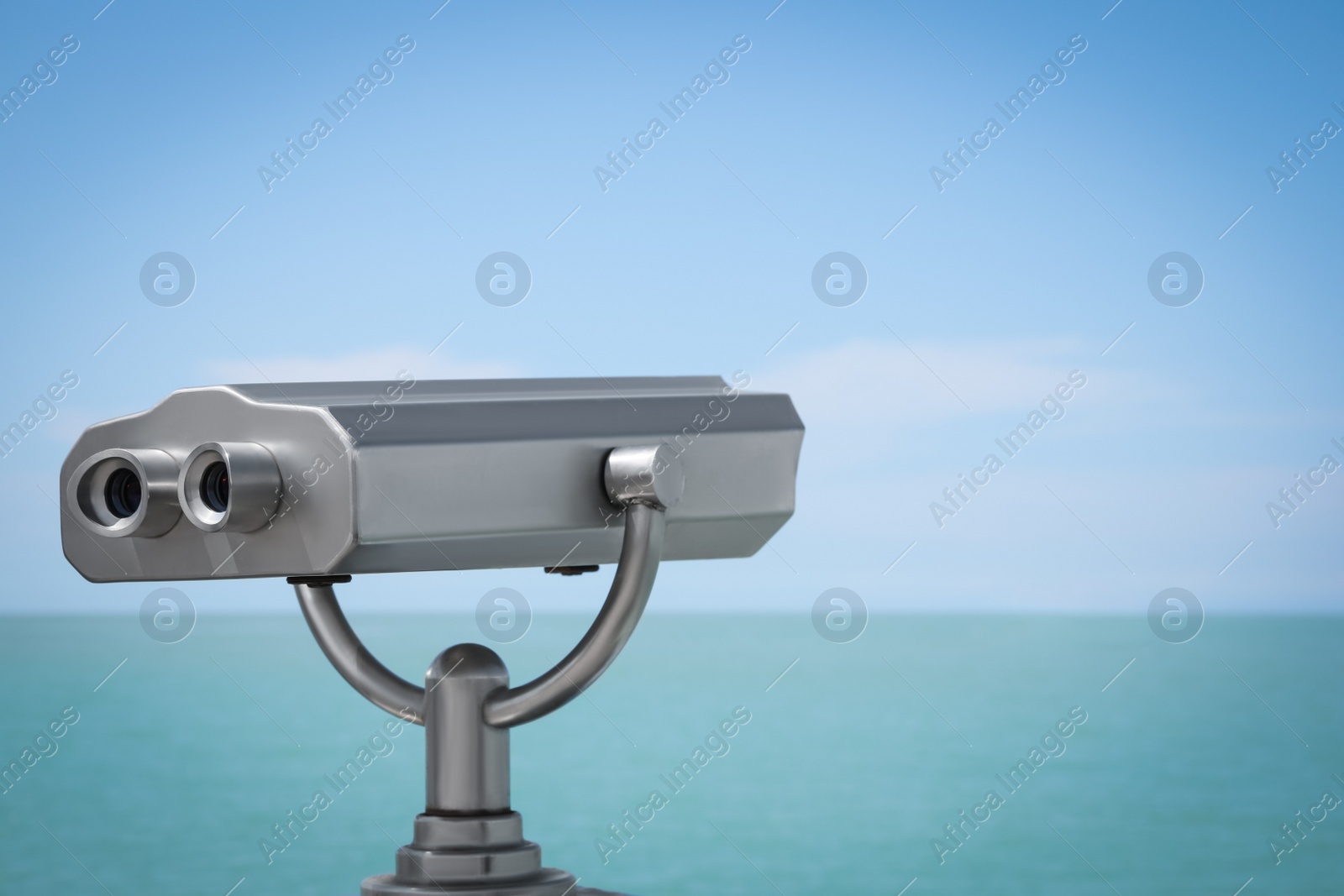 Photo of Metal tower viewer installed near sea, space for text. Mounted binoculars