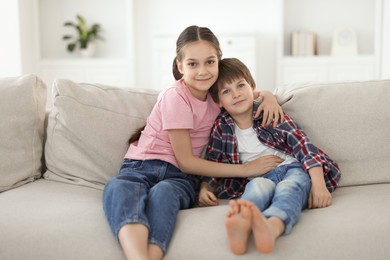 Photo of Happy brother and sister spending time together on sofa at home