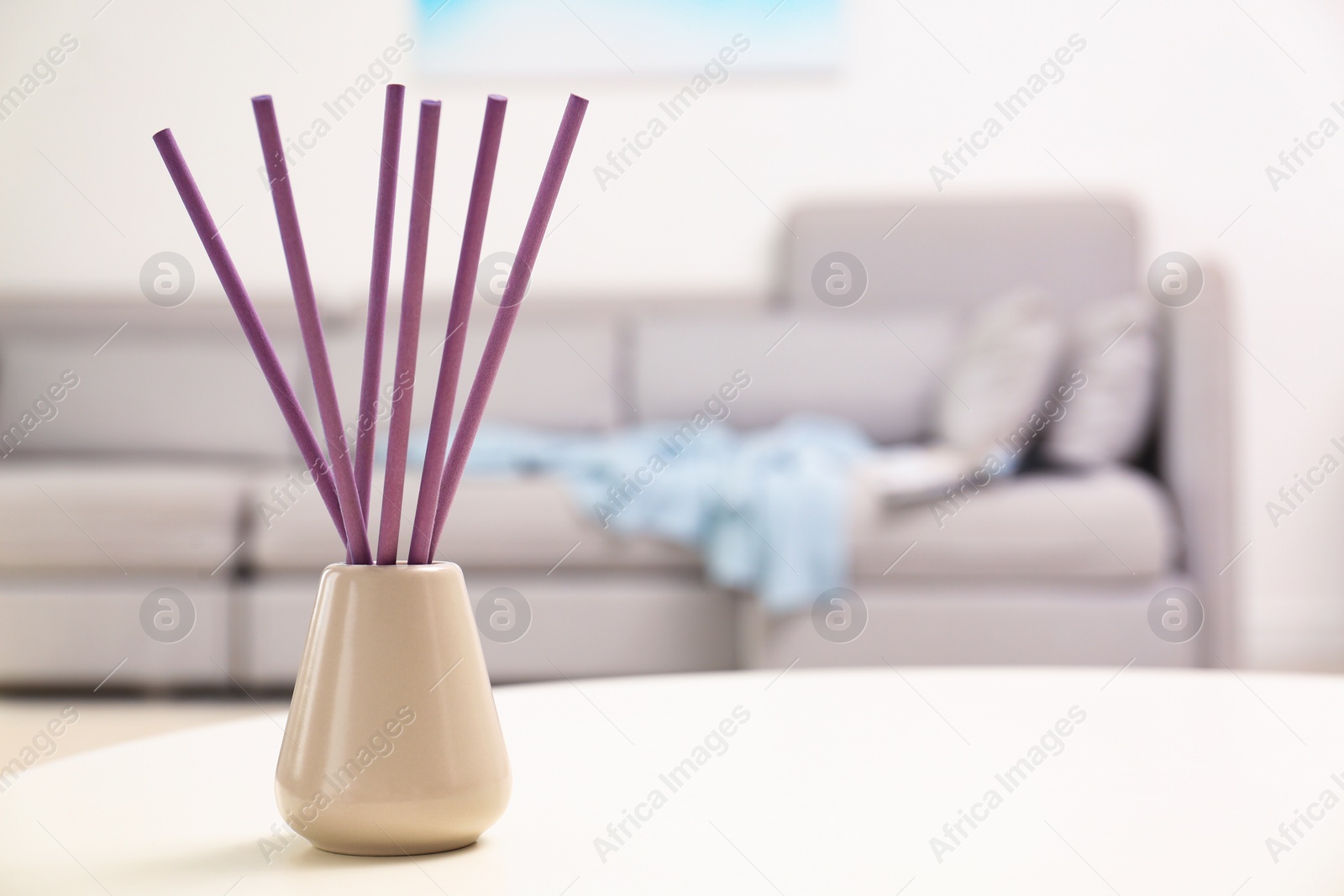 Photo of Reed air freshener with essential oil on table in room. Space for text