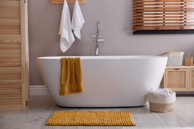 Soft orange mat on floor near tub in bathroom. Interior design