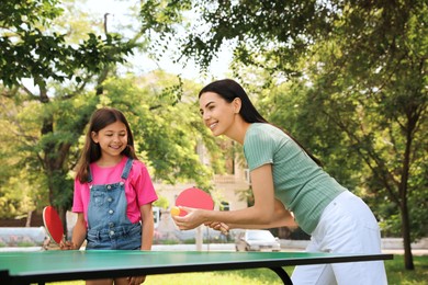 Photo of Young woman with her daughter playing ping pong in park
