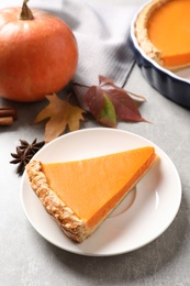 Plate with piece of fresh delicious homemade pumpkin pie on gray table