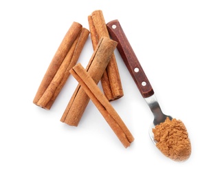 Photo of Aromatic cinnamon sticks and spoon with powder on white background