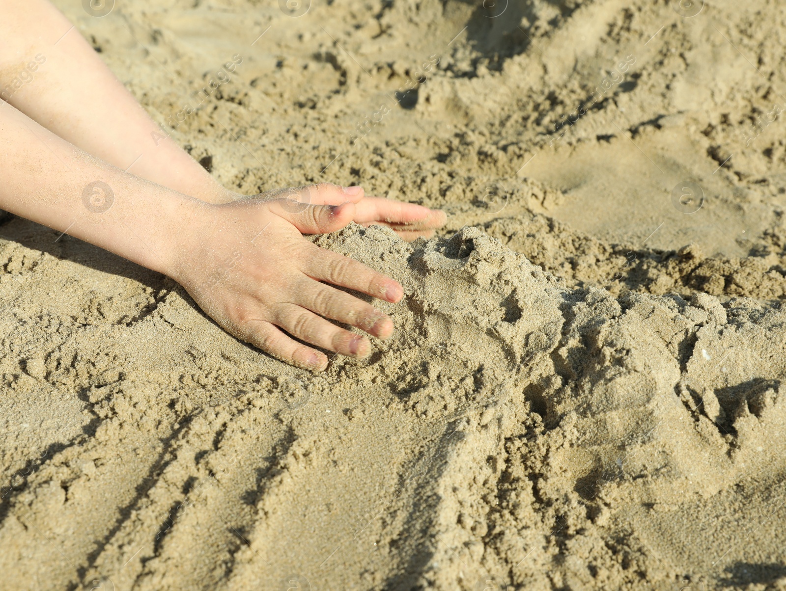 Photo of Little boy playing with sand on sunny day, closeup