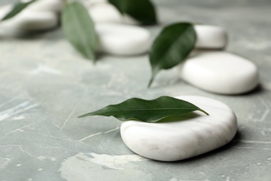 Spa stones and green leaves on grey background. Space for text