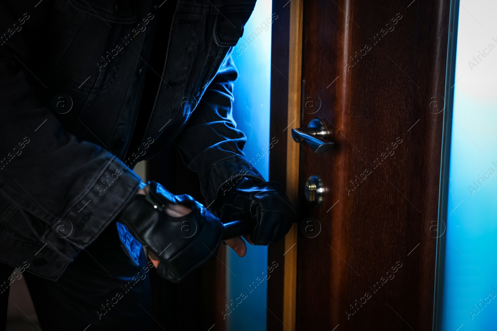 Photo of Man forcing door with crow bar, closeup. Dangerous criminal