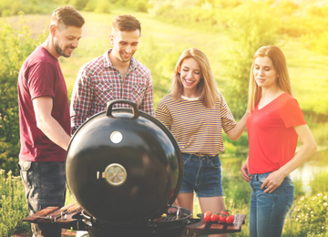 Image of Young people having barbecue in wilderness on sunny day
