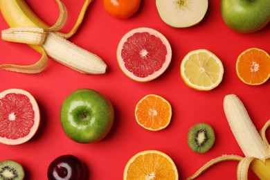 Photo of Different ripe fruits on red background, flat lay