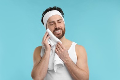 Photo of Washing face. Man with headband and towel on light blue background