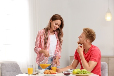 Photo of Happy young couple having breakfast at table in room