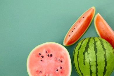 Cut and whole ripe watermelons on teal background, flat lay. Space for text