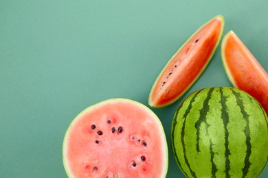 Photo of Cut and whole ripe watermelons on teal background, flat lay. Space for text