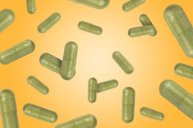 Image of Vitamin. Capsules falling on orange gradient background