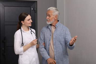 Young healthcare worker assisting senior man indoors