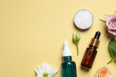 Flat lay composition with cosmetic serums on pale yellow background, space for text